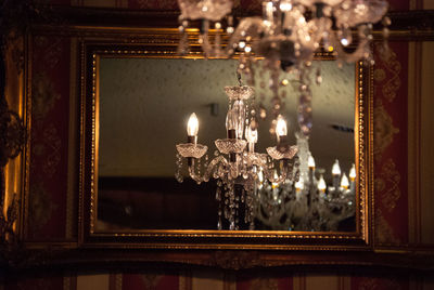 Illuminated chandelier reflecting in mirror