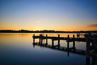 Pier on lake against sky during sunset