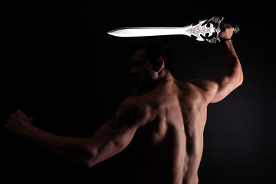 Midsection of shirtless man against black background