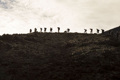 Silhouette people standing on land against sky