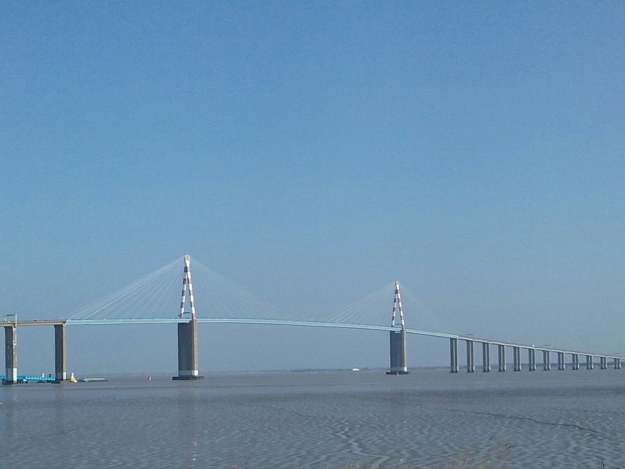 clear sky, copy space, connection, built structure, engineering, bridge - man made structure, suspension bridge, blue, architecture, bridge, transportation, sea, outdoors, long, water, golden gate bridge, day, travel destinations, tranquility, low angle view