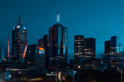 Illuminated buildings in city against sky at dusk