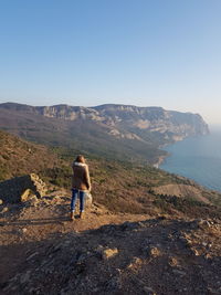 Rear view of man looking at mountain against sky