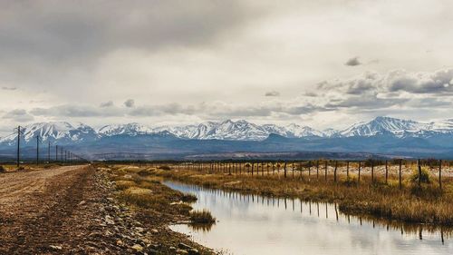 Scenic view of lake by snowcapped mountains against sky