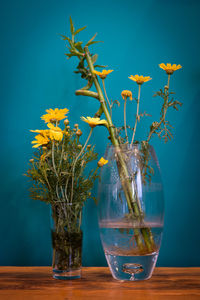 Bamboo and yellow flowers in glass vase