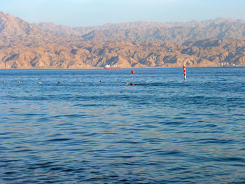 Scenic view of sea by rocky mountains