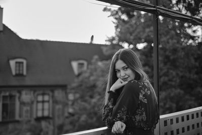 Portrait of young woman standing against building