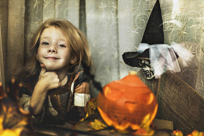 Portrait of young woman by window on the halloween decorations 
