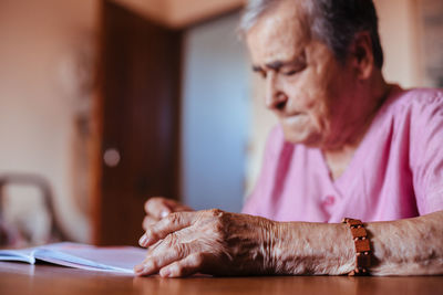 Side view of a senior woman with alzheimer's mental health issues painting on a notebook inside her home