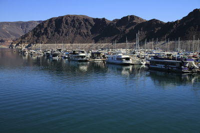 Boats moored at lake against mountains