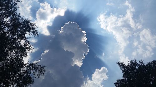 Low angle view of sunlight streaming through clouds