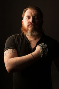 Portrait of man standing against black background