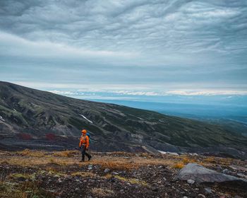 Rear view of man looking at mountains against sky