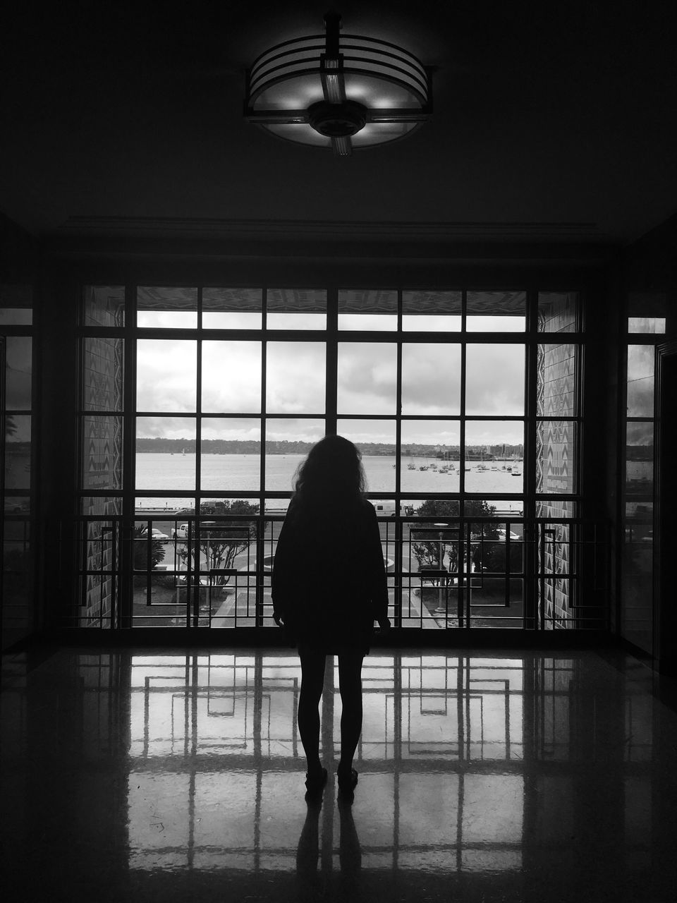 REAR VIEW OF MAN LOOKING THROUGH WINDOW