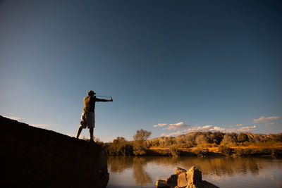 Man photographing by lake against sky