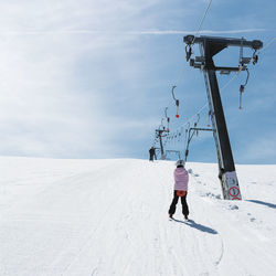 Rear view of girl standing on snow covered landscape against sky