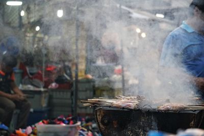 People on barbecue grill at market stall