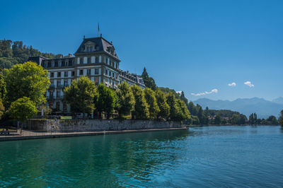 Buildings by river against sky