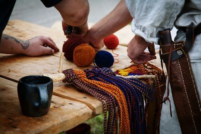 Midsection of men making wool craft product on table