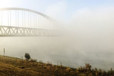 Bridge over river in foggy weather