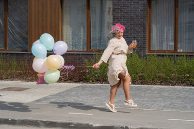 Full length of young woman standing on footpath