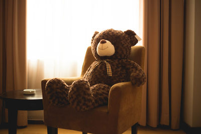 Teddy bear on armchair in living room at home