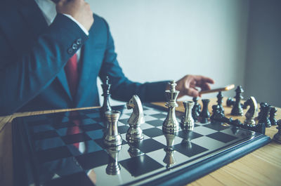 Midsection of businessman playing chess at office