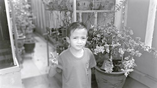 Portrait of boy standing by flowering plants