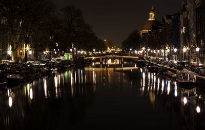 Illuminated canal amidst buildings in city at night