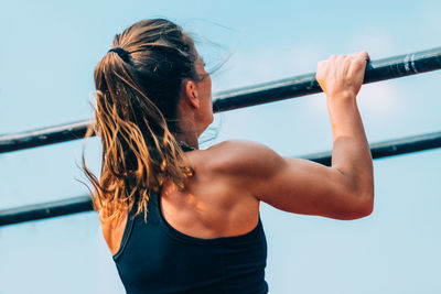 Woman exercising with poles against clear sky