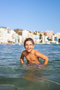 Funny kid into the water on an urban beach