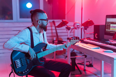 Young man sitting on guitar at music concert