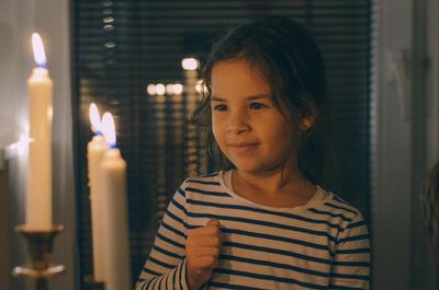 Close-up girl looking at illuminated candle