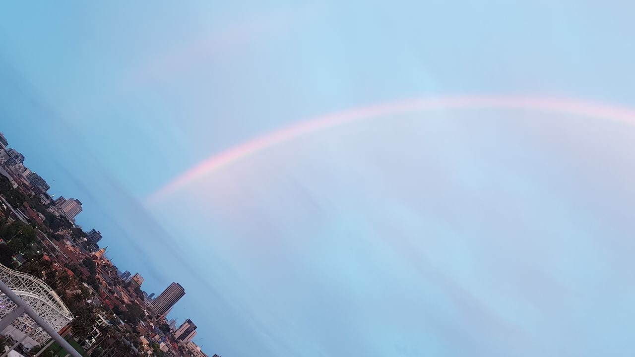 LOW ANGLE VIEW OF RAINBOW OVER BUILDING AGAINST BLUE SKY