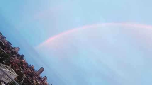 Low angle view of rainbow over building against sky