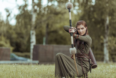 Beautiful archer holding bow and arrow while standing outdoors