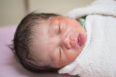 Close-up of cute newborn sleeping on bed at hospital