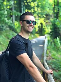 Portrait of young man wearing sunglasses standing against plants