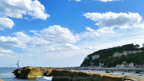 Side view of man fishing on rocky beach