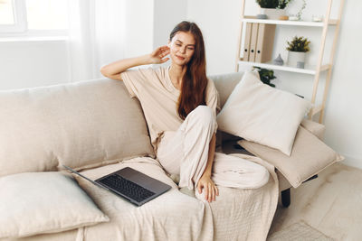 Young woman using phone while sitting at home