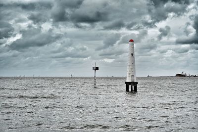 Lighthouse on beach against sky