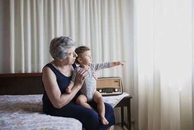 Grandmother sitting on bed with her grandson