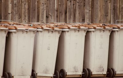 Close-up of trash cans against wooden wall