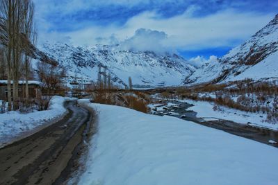 Snow covered road by mountain against sky