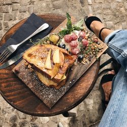 Low section of woman sitting by food served on table