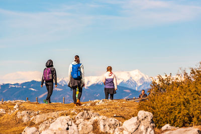 Rear view of people standing on rock against sky