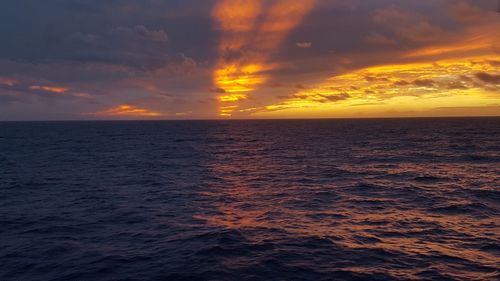 Scenic view of sea against dramatic sky during sunset