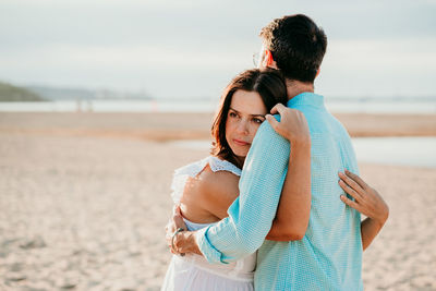 Friends standing on beach against sea