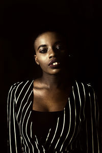 Portrait of young woman against black background