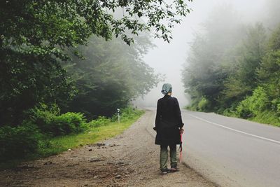 Rear view of people walking on road in forest